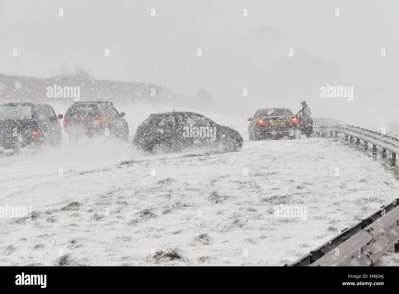 Lange Bredy, Dorset, Großbritannien. 18. März 2018. UK Wetter. (Reihenfolge der Bilder eines Unfalls 4 von 5) ein Auto zieht auf der Straße und schlägt die Leitplanken in der zentralen Reservierung, da der Fahrer nicht in der Lage ist, zu stoppen, stationäre Autos, Blizzard Bedingungen auf der A35 bei langen Bredy zwischen Bridport und Dorchester, Dorset als schwerer Schnee, der die Straße abgedeckt hat aufgehört haben zu vermeiden, macht das Fahren gefährlich. Foto: Graham Jagd-/Alamy Leben Nachrichten. Stockfoto