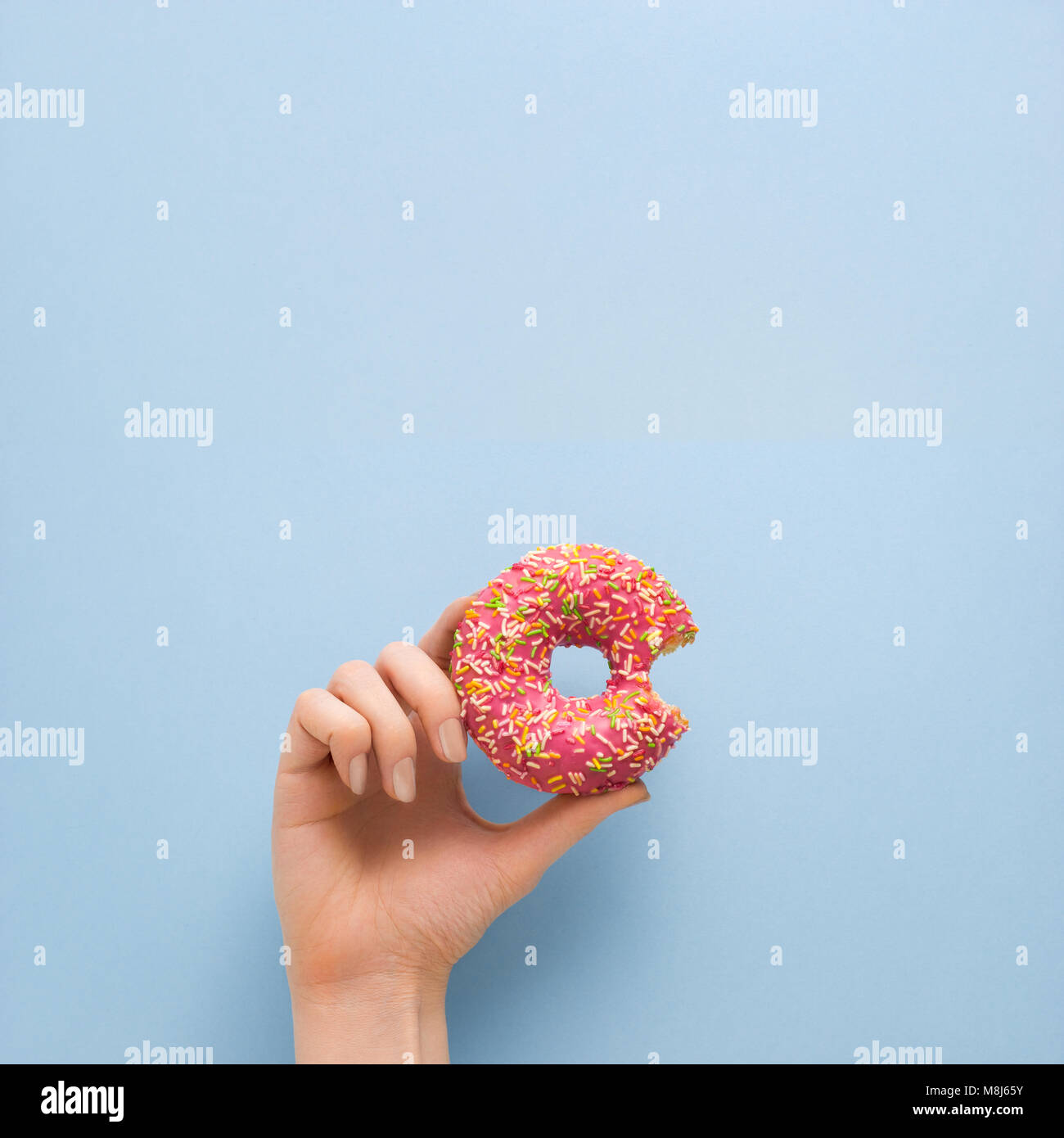 Kreatives Konzept Foto von Hand Donut auf blauem Hintergrund. Stockfoto