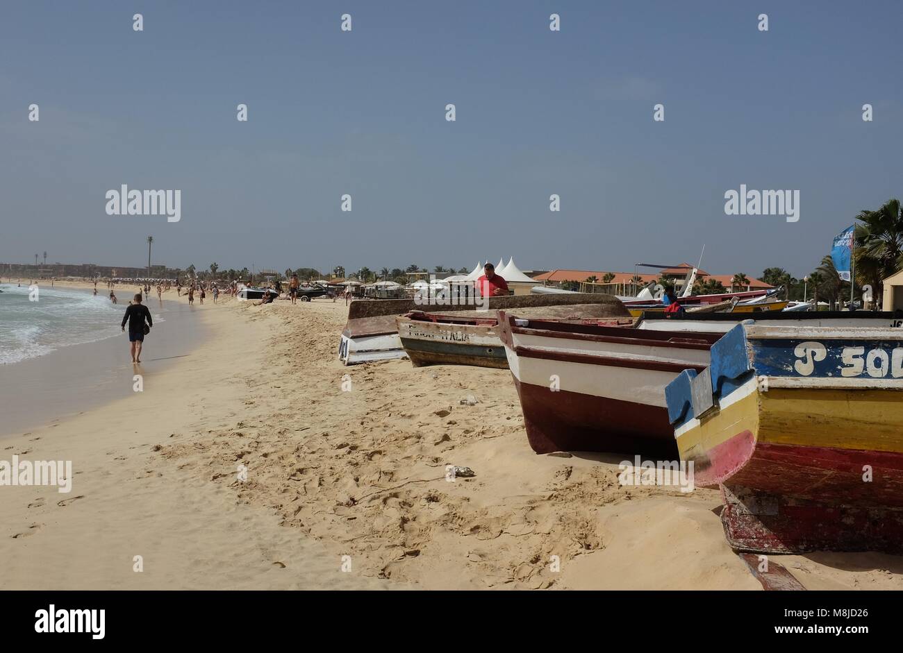 Strand an einem sonnigen Tag, in Santa Maria, Insel Sal, Kap Verde, einschließlich bunte Boote, Sand, Meer, blauer Himmel und Menschen. Stockfoto