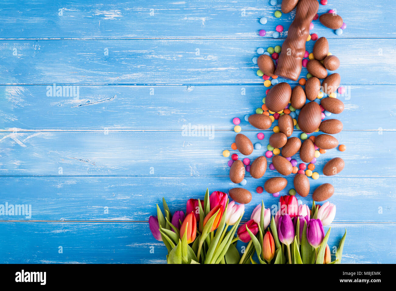 Ostern blauer Hintergrund mit Schokolade Hasen, Ostereier und Tulpen Stockfoto