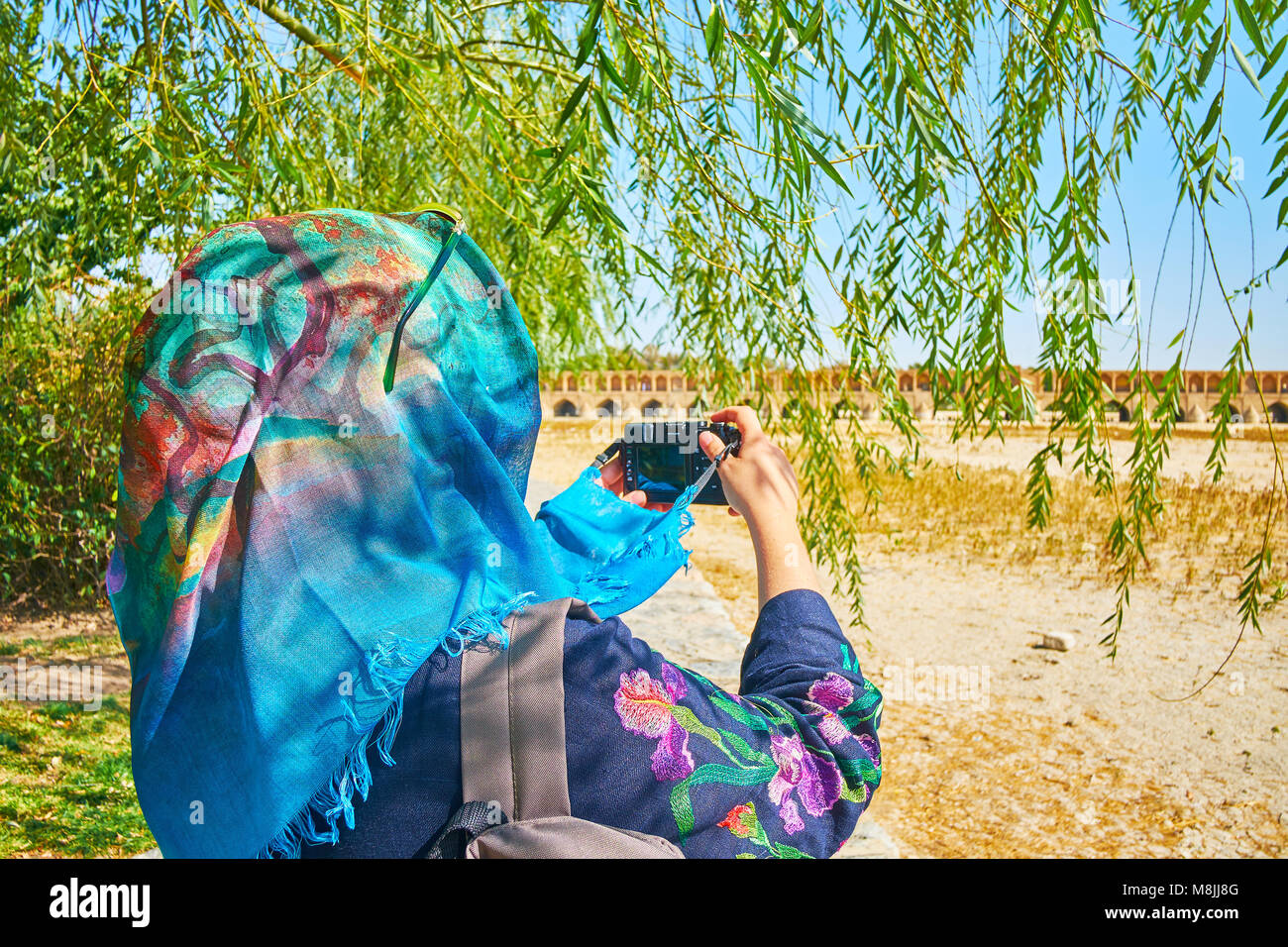 Weibliche torist im hijab macht das Foto von Si-o-se-pol Brücke durch die weidenzweige, Koudak Park, Isfahan, Iran. Stockfoto