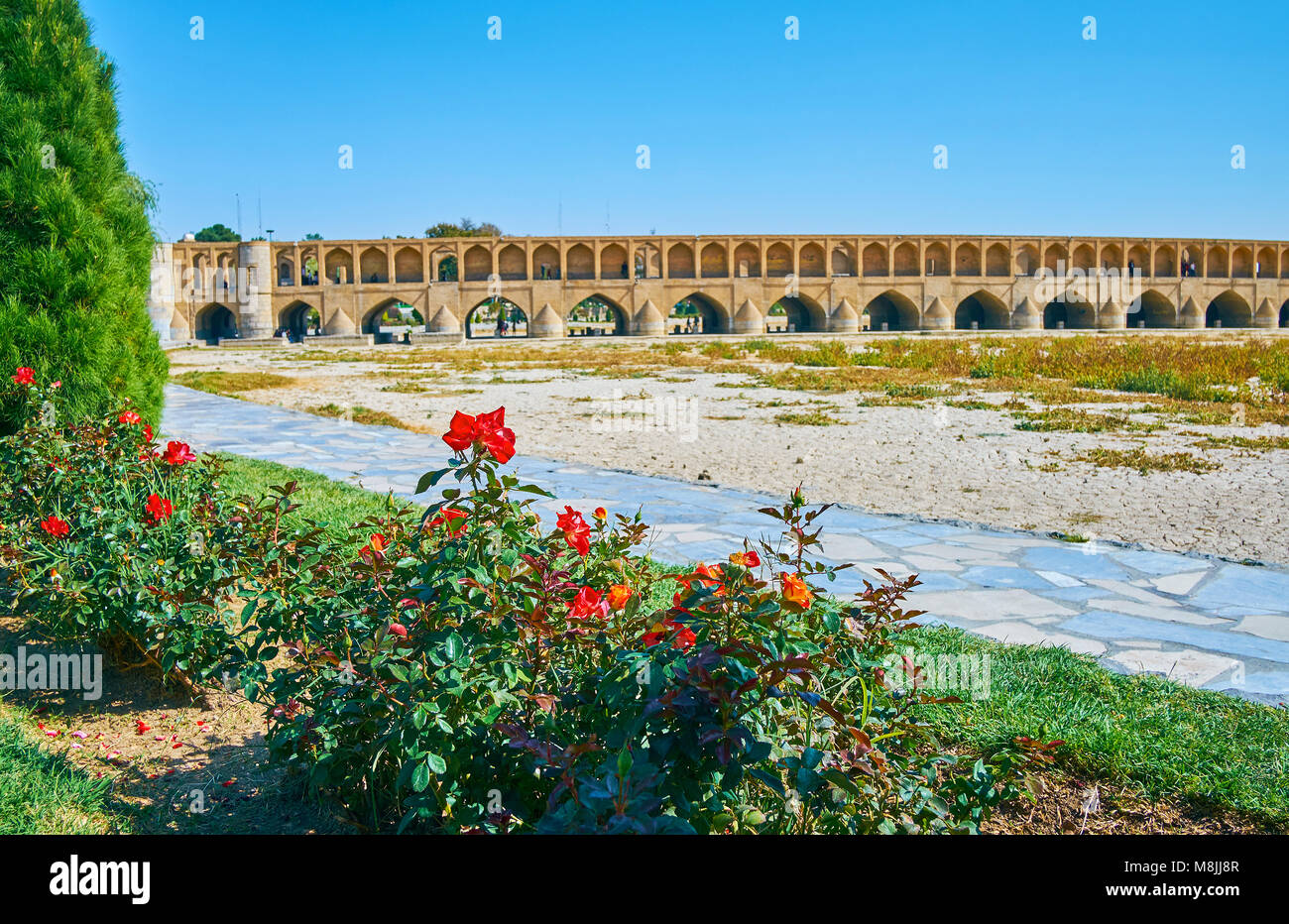Die historische erhalten Si-o-se-pol Brücke hinter dem roten Rosenstöcken der Koudak Park, Isfahan, Iran. Stockfoto