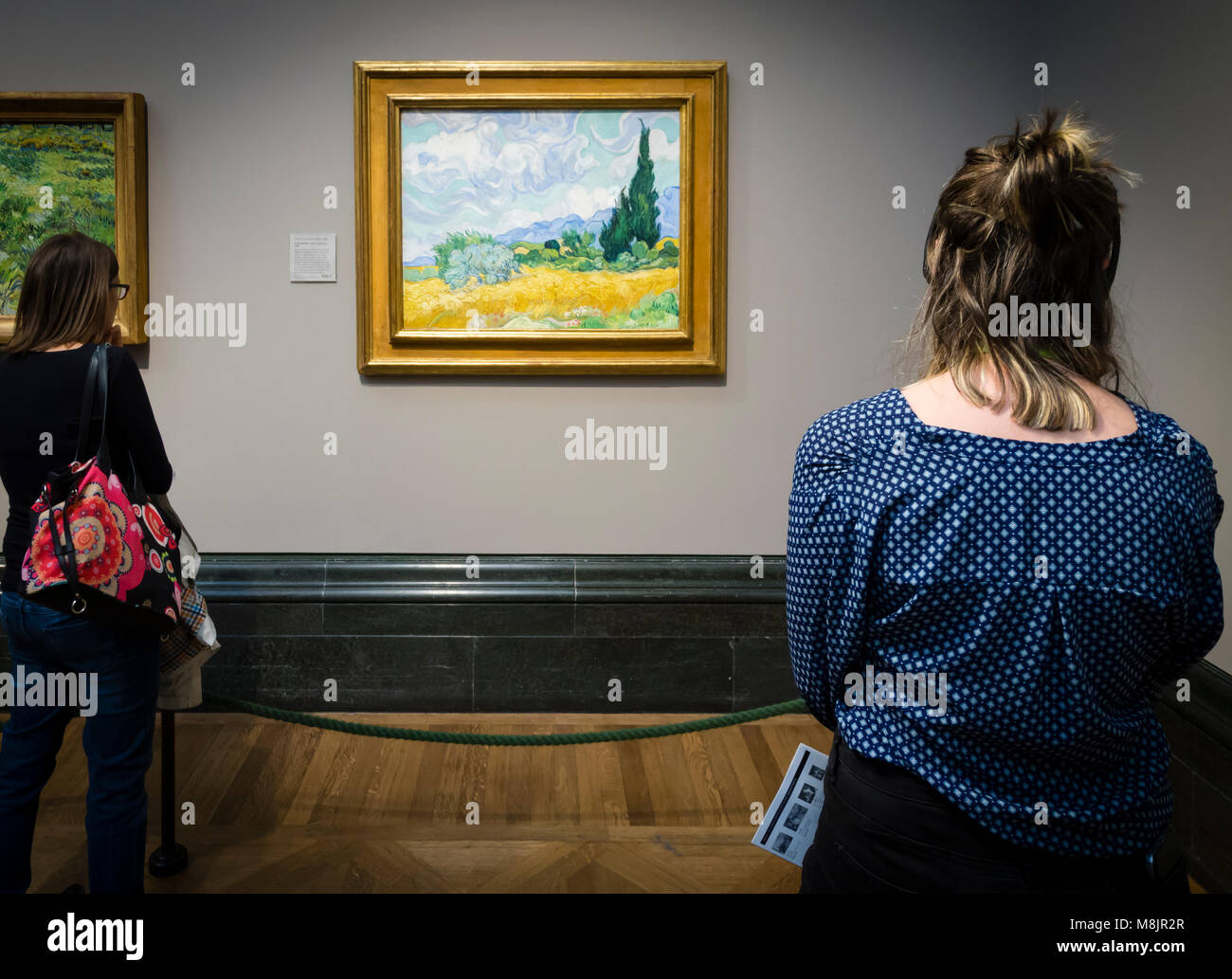London, Großbritannien - 1 May 2017: Besucher des Londoner National Gallery sehen Vincent van Goghs berühmten Öl Gemälde "EIN Wheatfield, mit Zypressen. Stockfoto