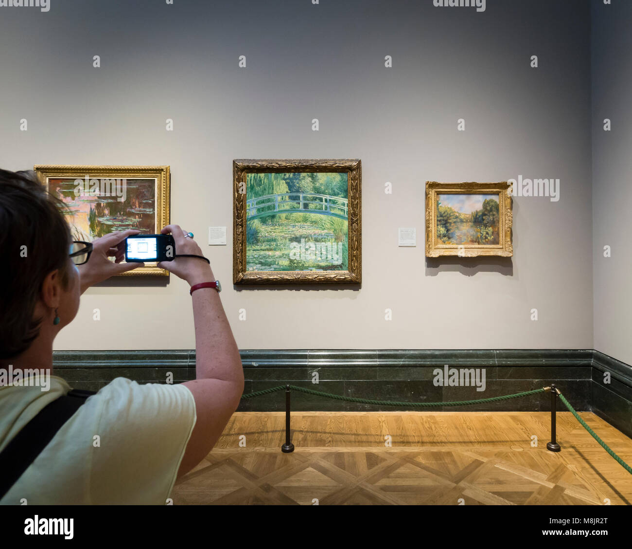 London, Großbritannien - 1 May 2017: ein Besucher des Londoner National Gallery ist mit seinen Smartphones Bilder von berühmten Öl Claude Monets Water-Lily' Gemälde "Der Teich". Stockfoto