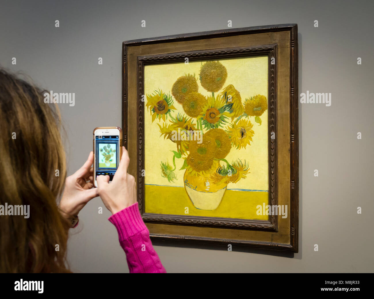 London, Großbritannien - 1 May 2017: ein Besucher des Londoner National Gallery ist unter Verwendung Ihres Smartphones, um Bilder von Vincent van Gogh's Öl Malerei unflowers', eines der bekanntesten Exponate des Museums. Stockfoto