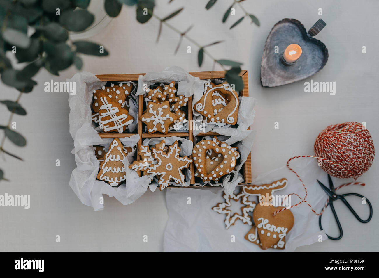 Eine Box mit Lebkuchen Cookies auf eine Tabelle mit Kerze Stockfoto