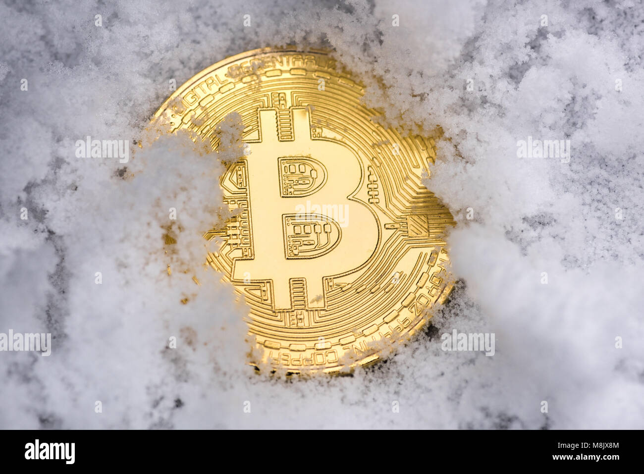 Ein gold Bitcoin ruht im Schnee Stockfoto