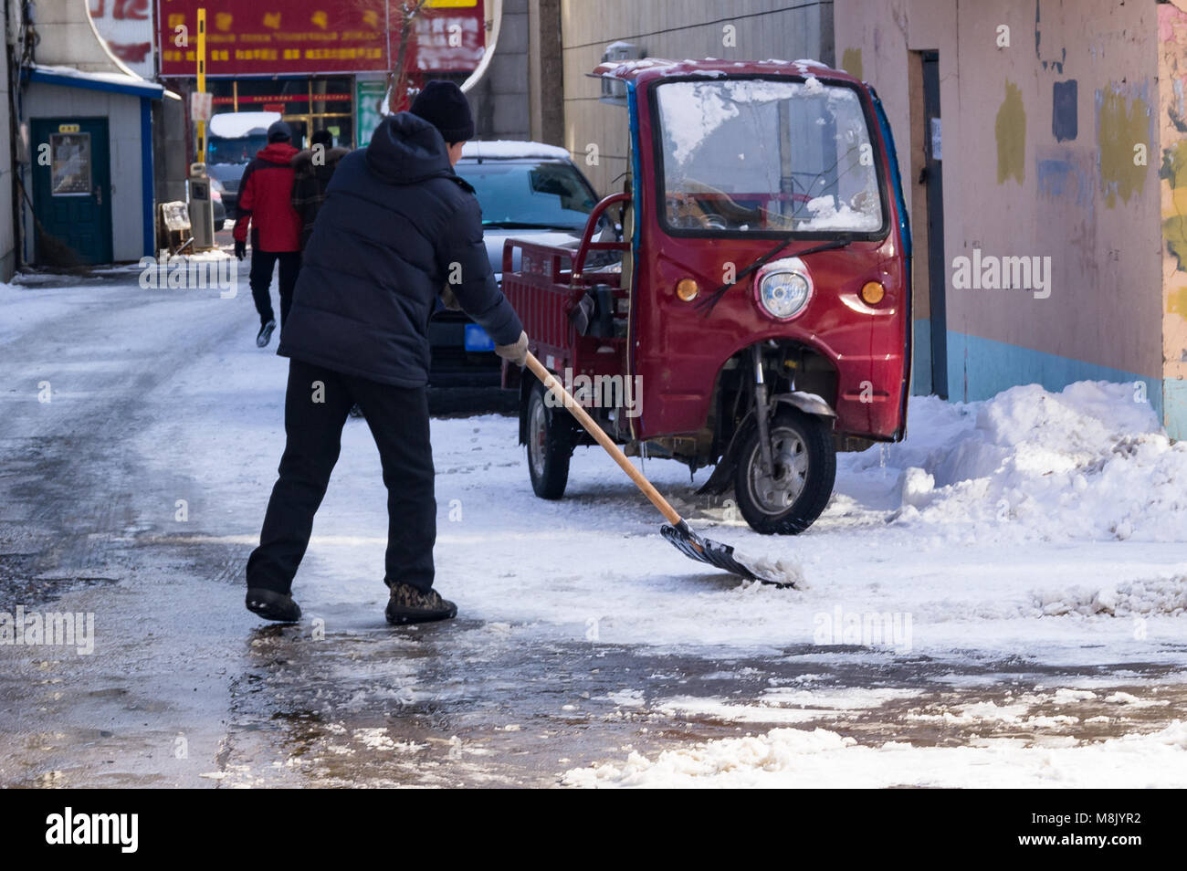 Reinigung der Schnee mit einer Schaufel nach einem starken Schneefall. Ein Mann entfernt Schnee auf einer Straße der Stadt von China Stockfoto