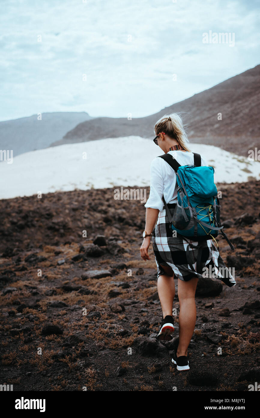 Frau Wanderer Wandern auf kargen felsiges Gelände unter schwarzen vulkanischen Felsen und weißen Sanddünen. Sao Vicente Kap Verde Stockfoto