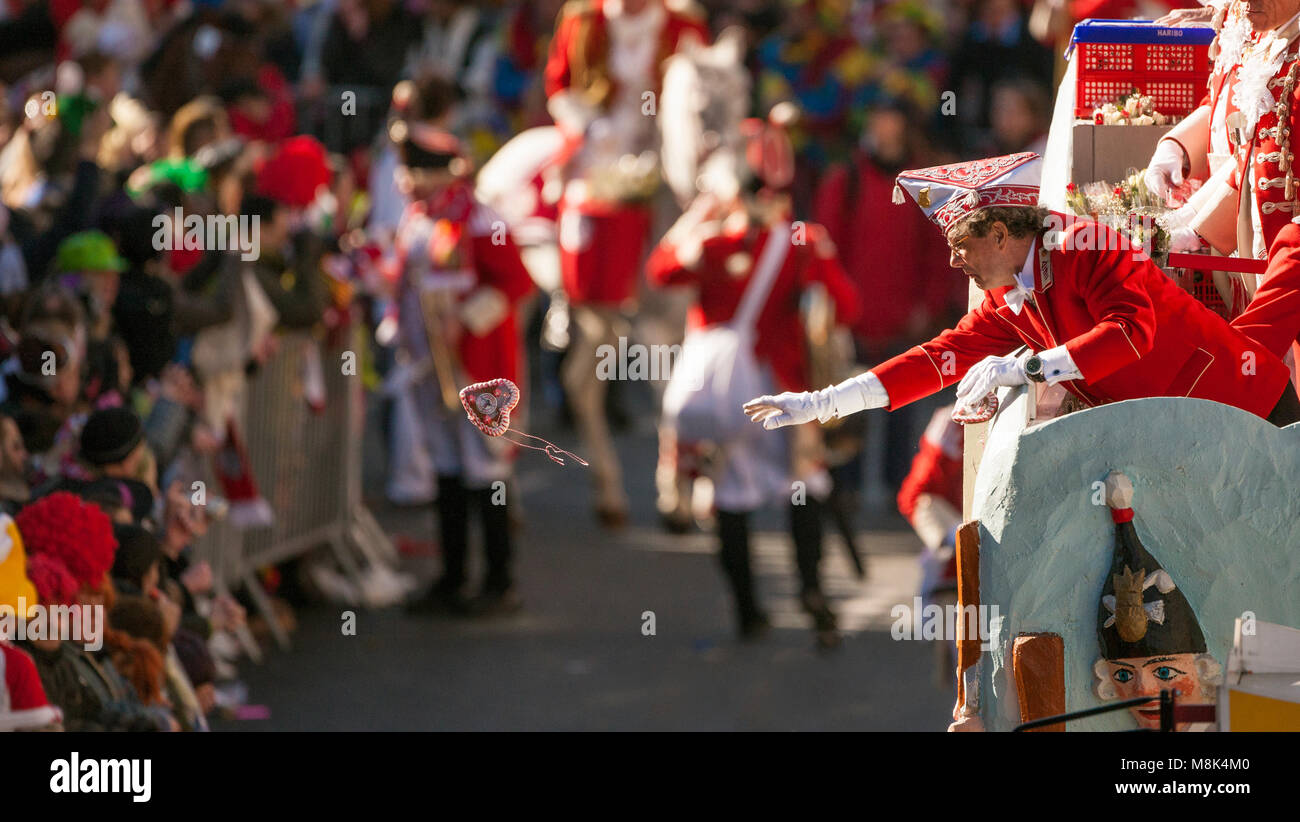 Karneval Clown am Rose Montag Parade in Köln wirft ein Lebkuchenherz in die Menge. Stockfoto