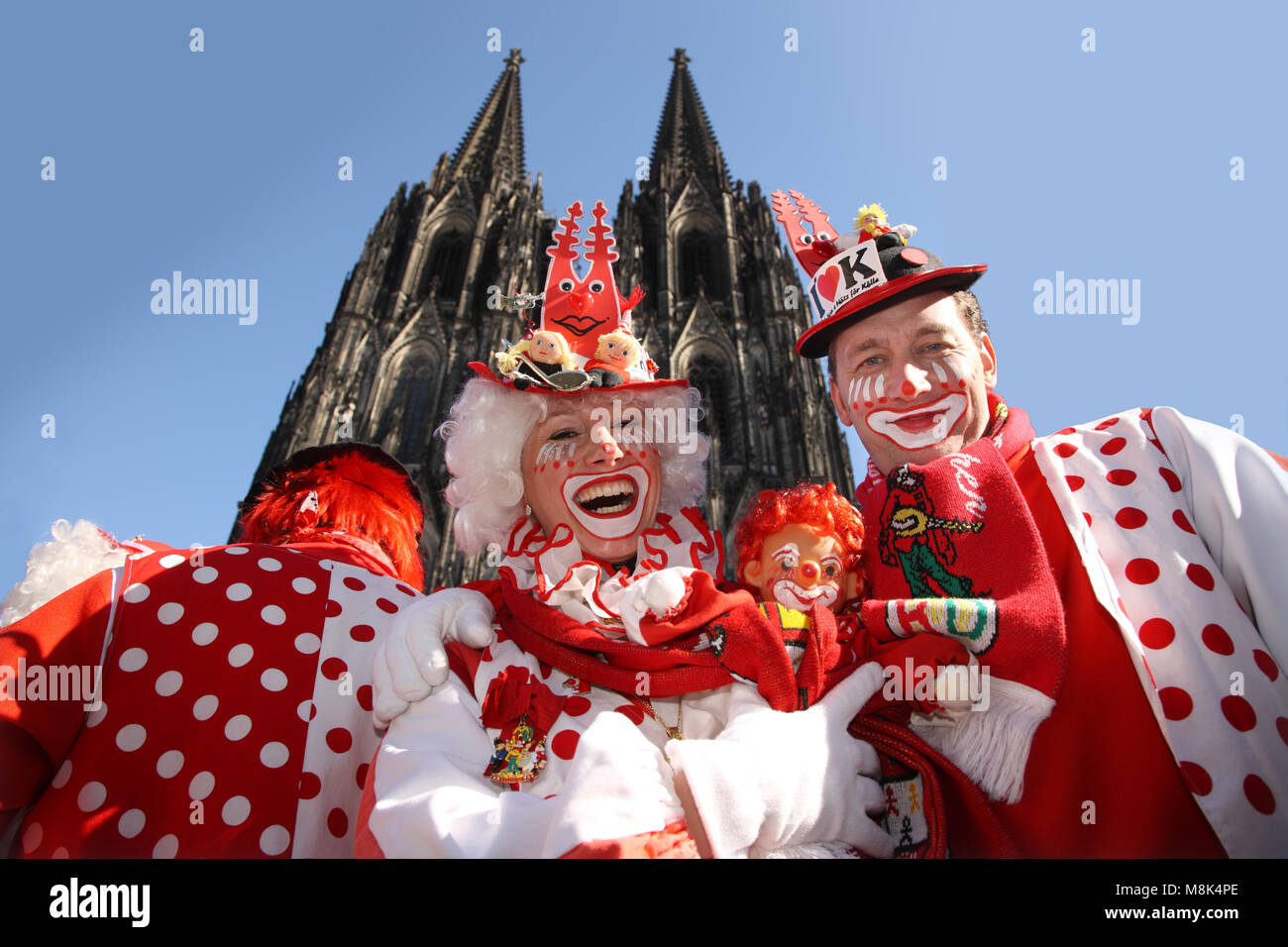 Kölner Karneval Clowns posiert vor dem Kölner Dom auf Rose Montag. Kostüme sind Rot und Weiß, das sind die Farben von Köln. Stockfoto