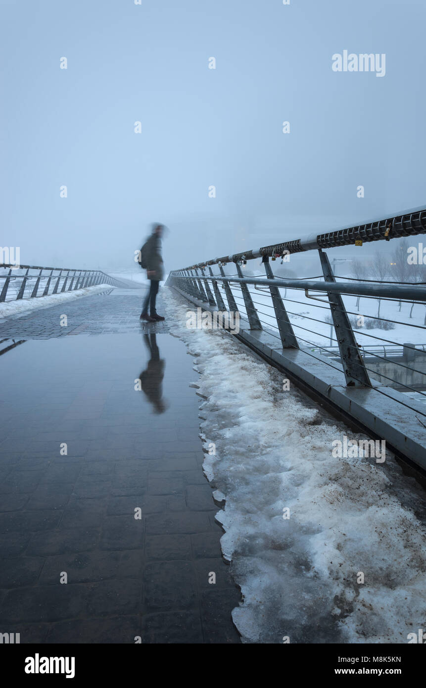 Unscharfe Silhouette eines Mannes, der durch eine Fußgängerbrücke und in Pfützen obskuren im dichten Nebel reflektiert. Mystische Hintergrund Stockfoto