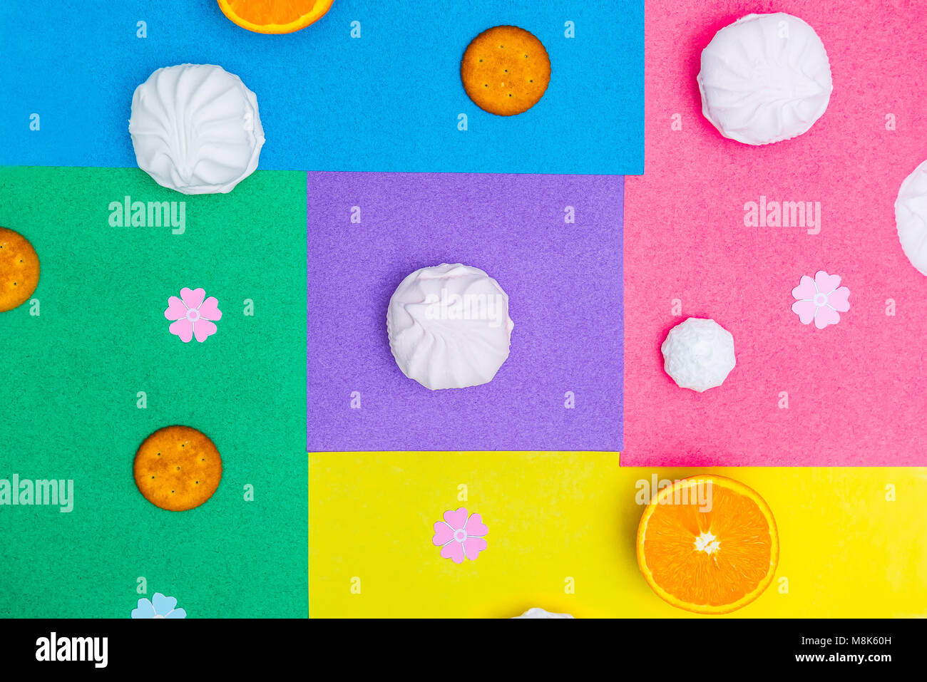 Verschiedene runde Süßigkeiten - Cookies, Baiser, Eibisch über mehrfarbige hellen Hintergrund. Süßigkeiten Minimalismus Geometrie Konzept. Ansicht von oben, selektive konzentrieren. Stockfoto