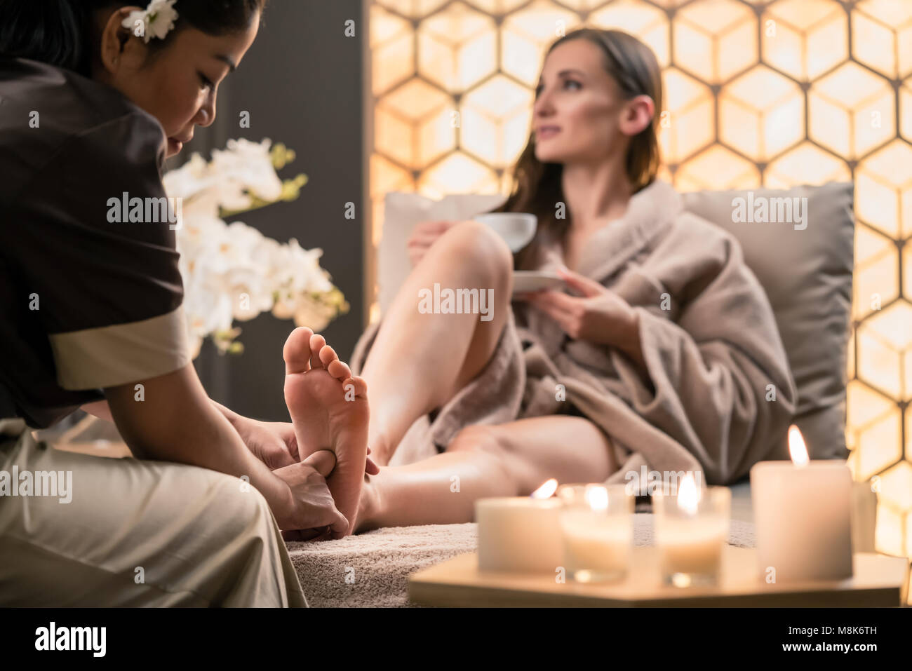 Therapeut massiert den Fuß eines weiblichen Klienten in Asiatische Schönheit Stockfoto