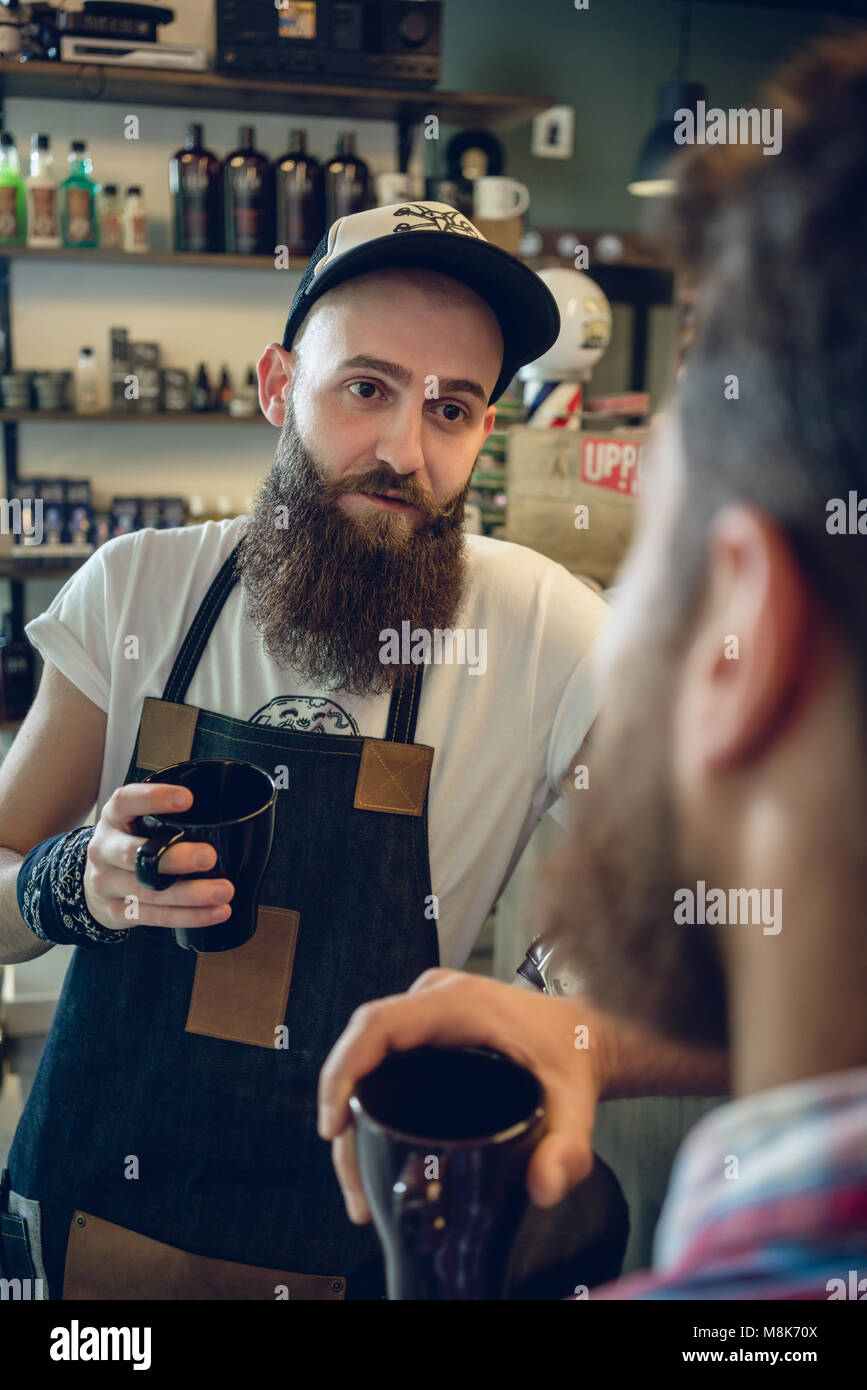 Dedizierte hairstylist Kaffee trinken, mit seinem Kunden und Freund Stockfoto