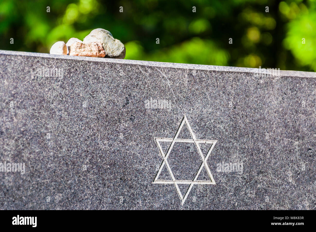Steine auf jüdische Gedenkstätte Granitplatte mit David Stern. Es ist eine jüdische Tradition kleine Steine zu nehmen und verlassen oder Sie auf memorial Platten Stockfoto