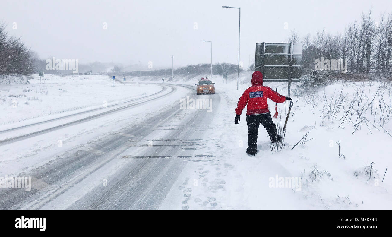 Ein Mitglied des Nordens Dartmoor Such- und Rettungsteam Uhren ein Autofahrer fahren entlang einer Straße in der Nähe von Okehampton in Devon als schweren Schnee Verkehrschaos zu Teilen der South West gebracht. Stockfoto