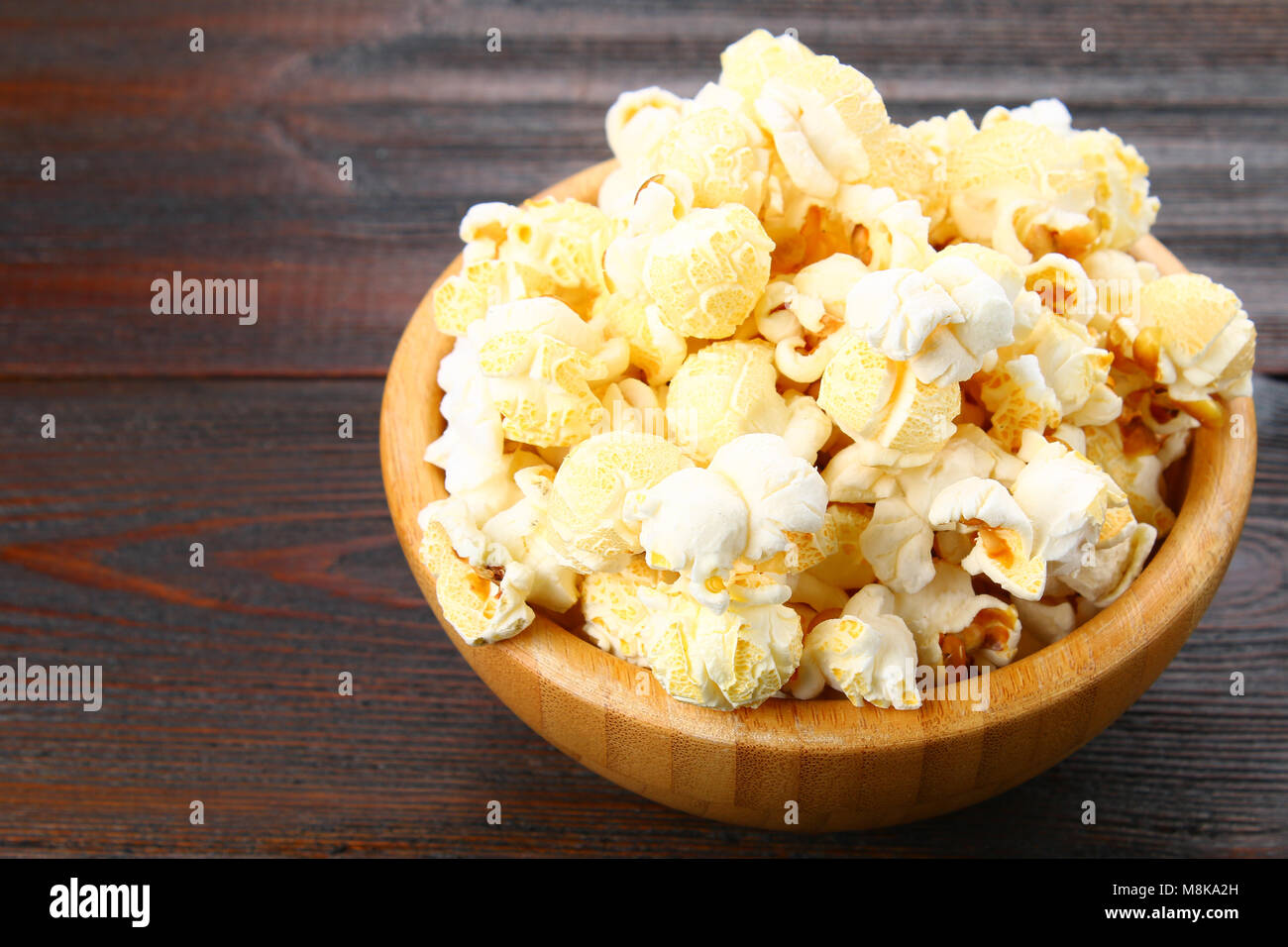Gesalzene Popcorn in eine hölzerne Schüssel auf einen hölzernen Tisch Stockfoto