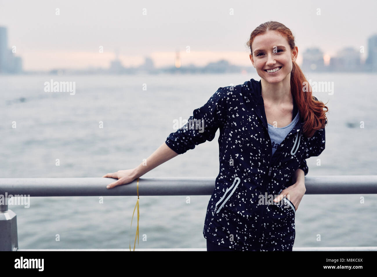 Junge kaukasier Frau lächelt entlang dem Hudson Rive in New York City Stockfoto