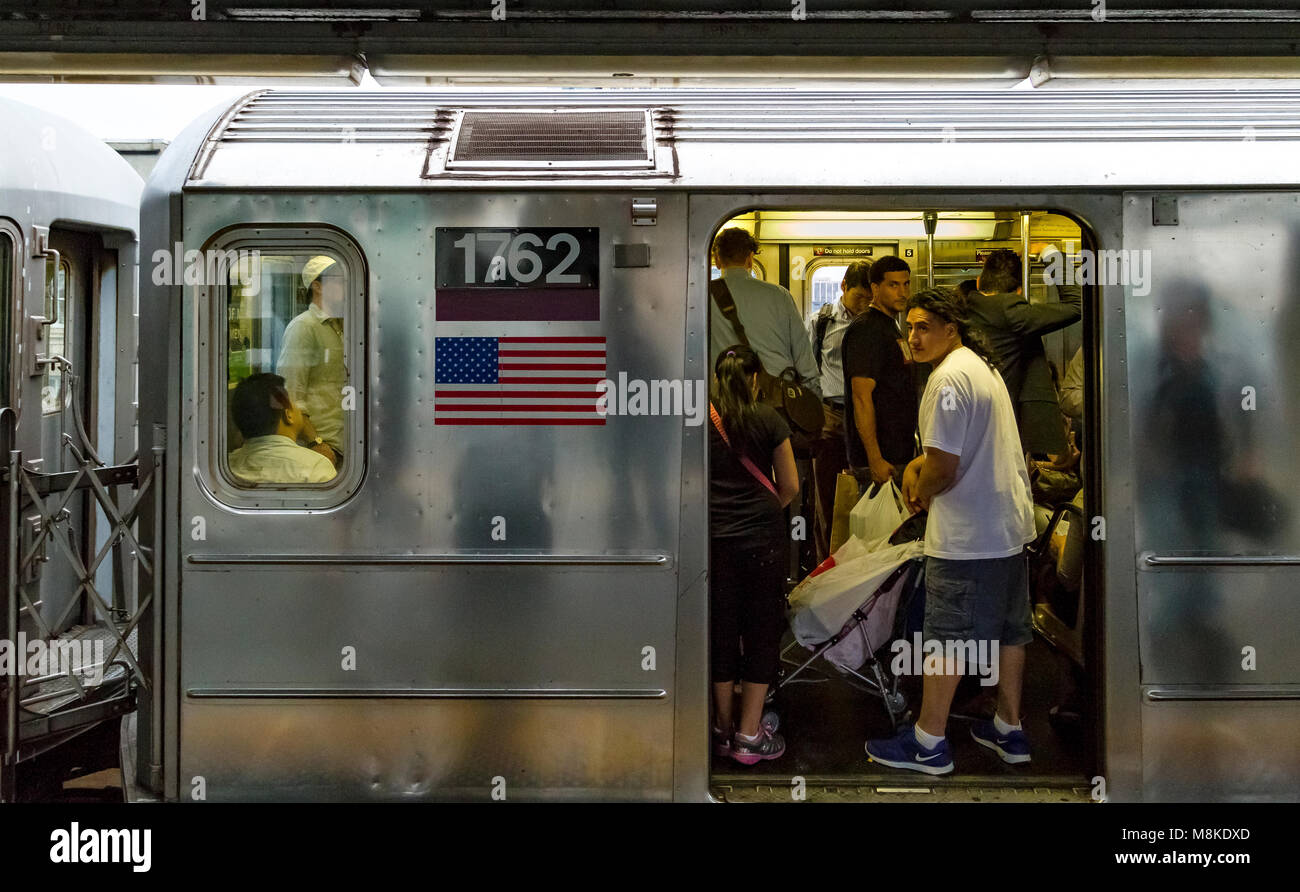 Ein New Yorker U-Bahn-Zug voller Leute an der U-Bahn-Station Queensboro Plaza, Queens, New York Stockfoto