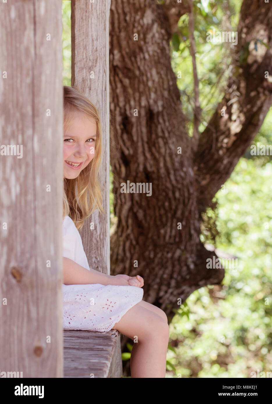 Kleines Mädchen sitzt auf einer Veranda barfuß Stockfoto