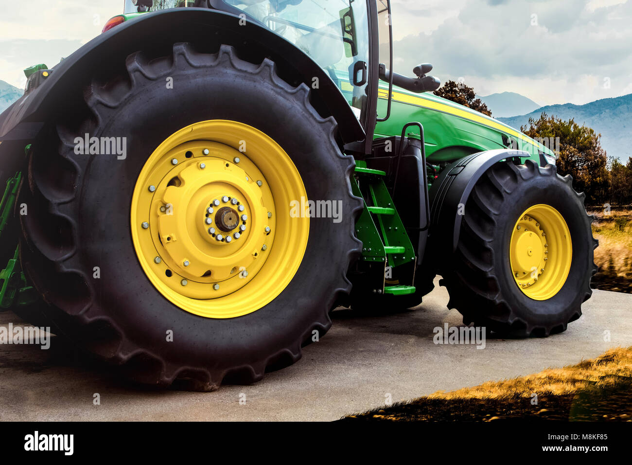 Grünen Traktor mit gelben Räder, vor dem Hintergrund des Feldes, Seitenansicht, Hintergrundbild Stockfoto