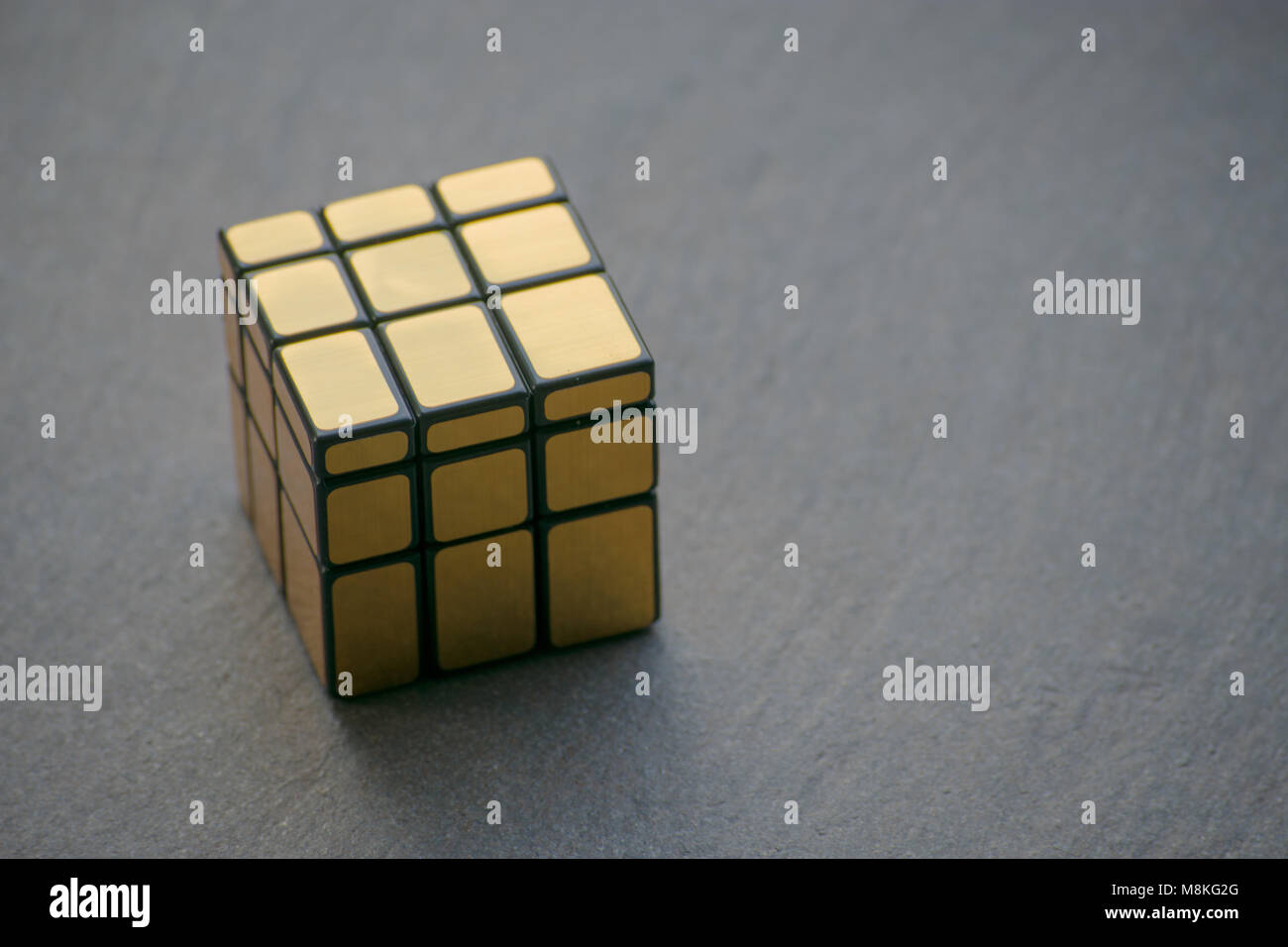Golden 3d-Rubik's Cube liegen auf einem grauen Steinboden. Stockfoto