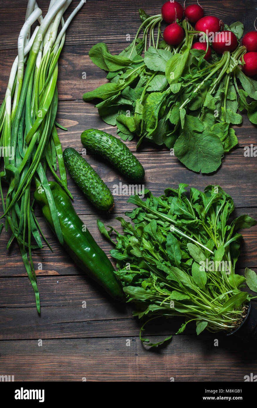 Frühling Hintergrund mit frischen saftigen Gemüse wie grüne Zwiebeln, Rucola, Gurken und Radieschen. Gesunde Ernährung Konzept. Veganes essen. Stockfoto