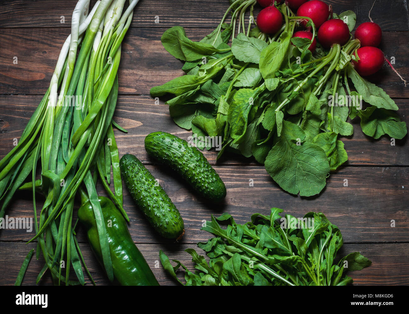 Frühling Hintergrund mit frischen saftigen Gemüse wie grüne Zwiebeln, Rucola, Gurken und Radieschen. Gesunde Ernährung Konzept. Veganes essen. Stockfoto