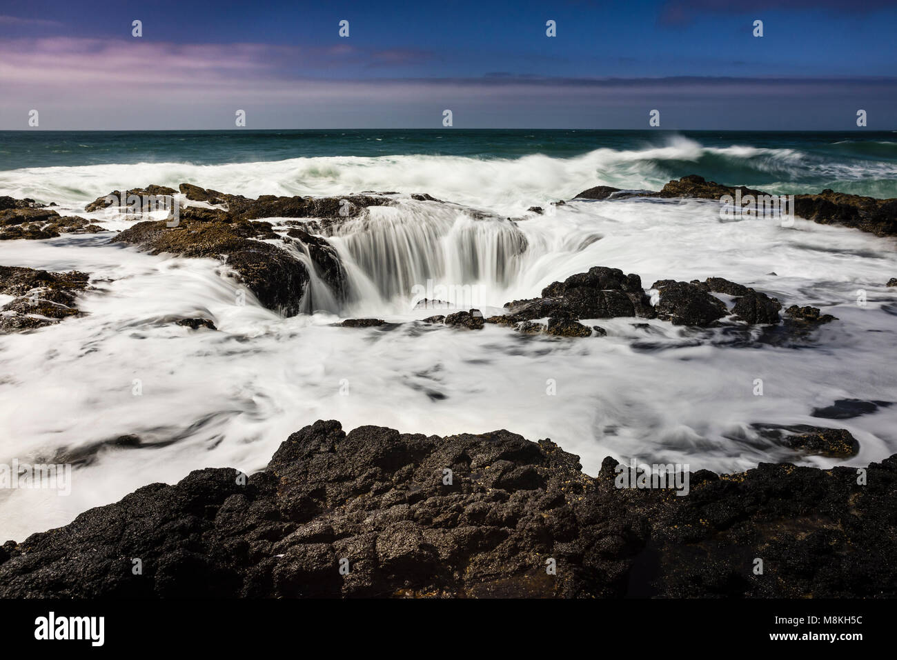 Thor ist gut am Cape Perpetua auf der Oregon Küste südlich von Florenz, Oregon ist eine natürliche Felsformation, die Abflüsse der Absturz der Brandung, wie es ist, die ein Ablassen. Stockfoto