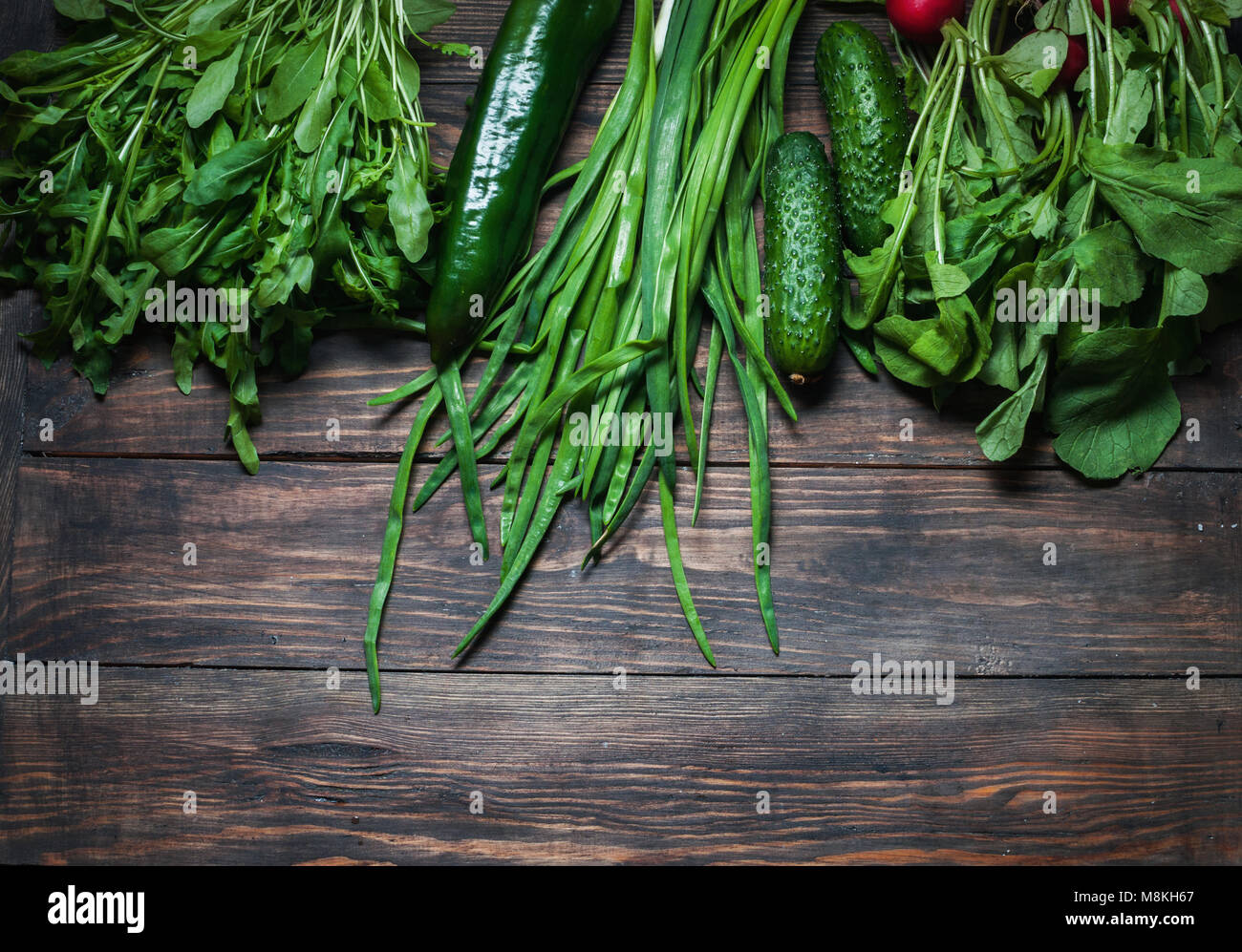 Frühling Hintergrund mit frischen saftigen Gemüse wie grüne Zwiebeln, Rucola, Gurken und Radieschen. Gesunde Ernährung Konzept. Veganes essen. Platz für writi Stockfoto
