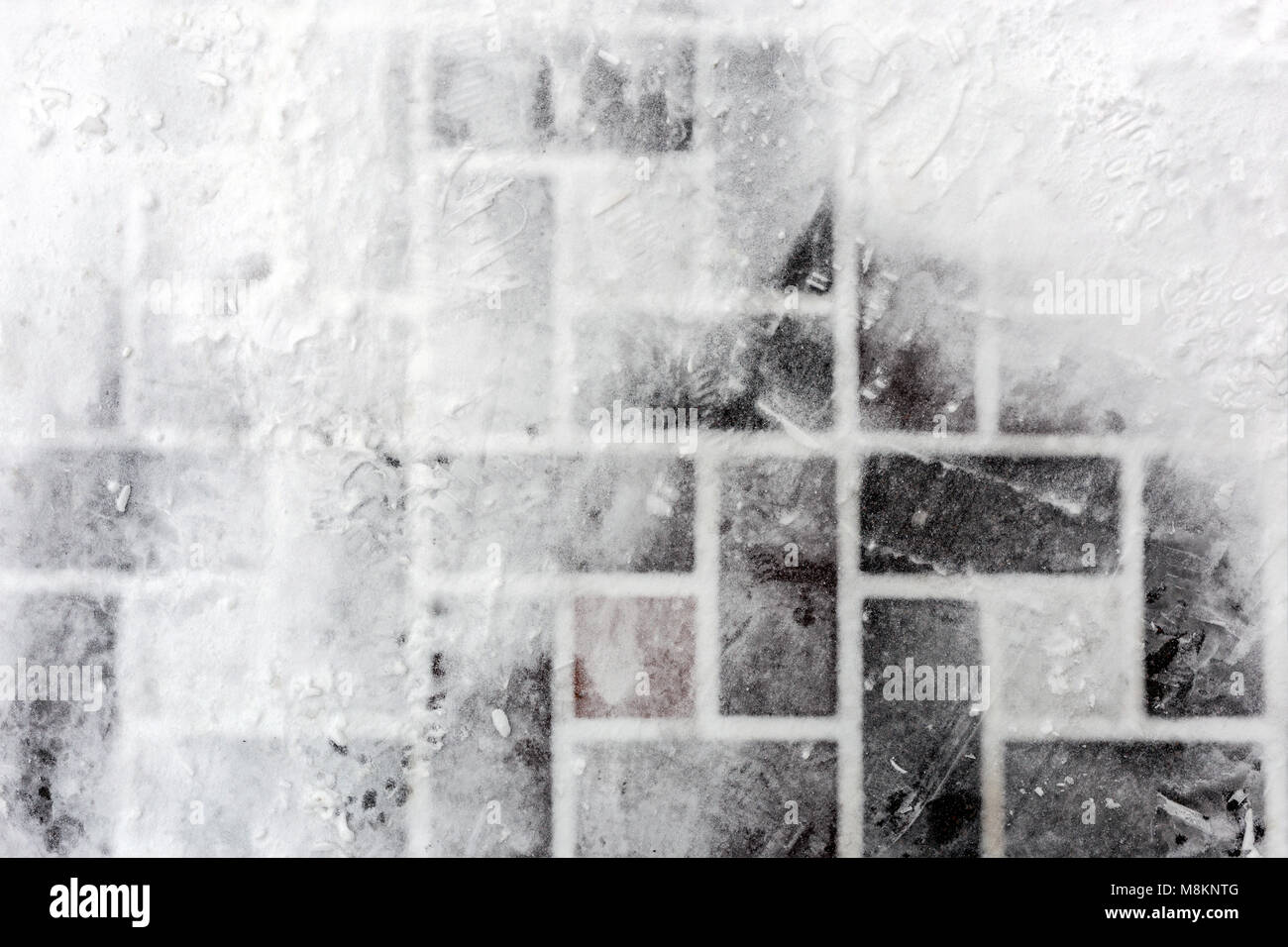 Fliesen- Pflaster mit Schnee bedeckt. Fußabdrücke auf rutschigem  Untergrund. Abstrakte winter Textur. Copyspace für Text Stockfotografie -  Alamy