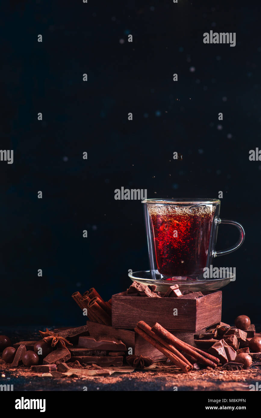 Tee in einem doppelwandigen Schale auf einem Stapel mit Spice Boxes. Zimt, gebrochene Schokolade Stücke, Kakaopulver und Anis Sterne. Dessert kochen Co Stockfoto