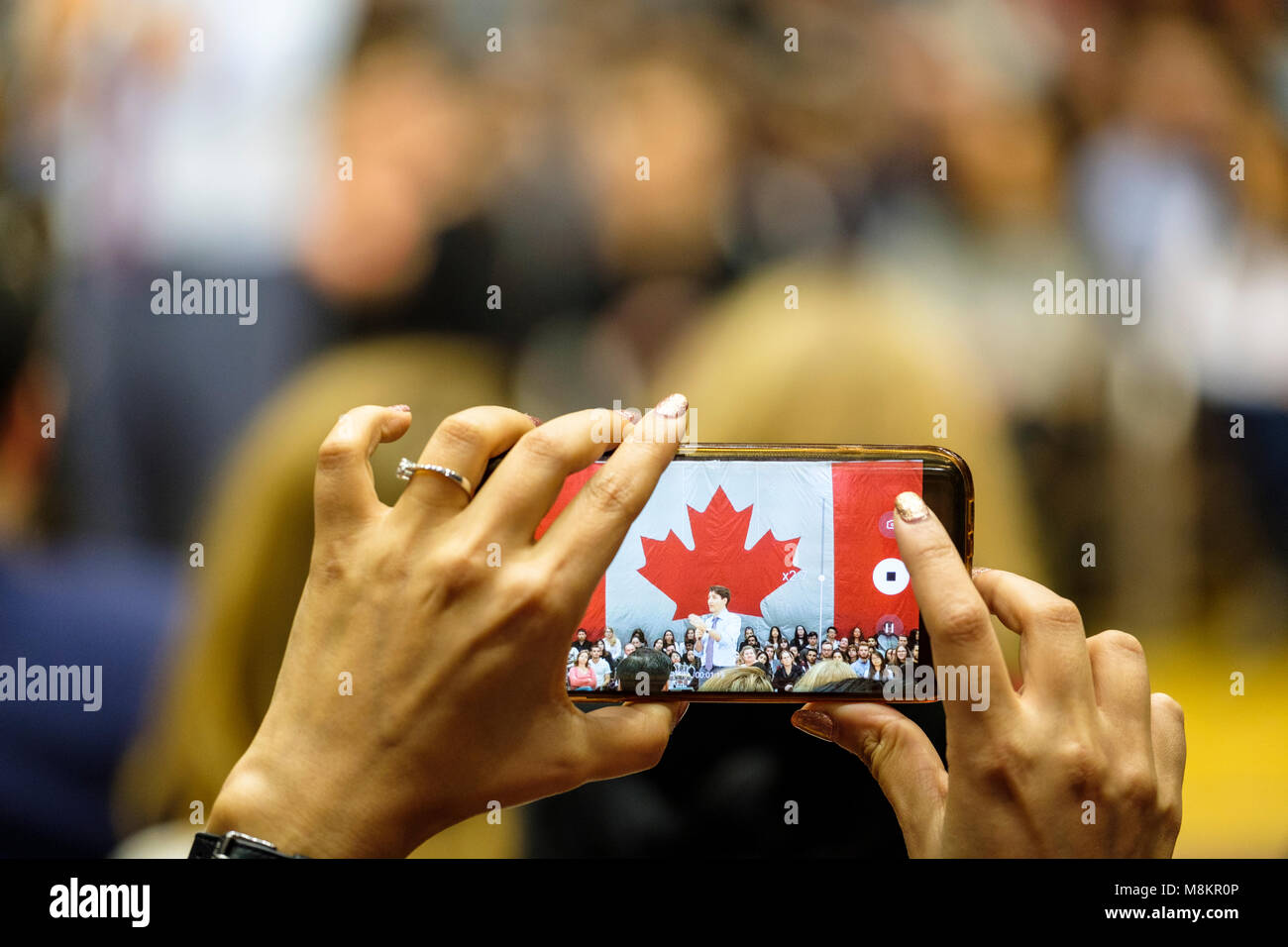 Hände von einer Frau mit einem Handy ein Bild von Justin Trudeau, Premierminister von Kanada, einem Town hall Meeting in London, Ontario, Kanada. Stockfoto