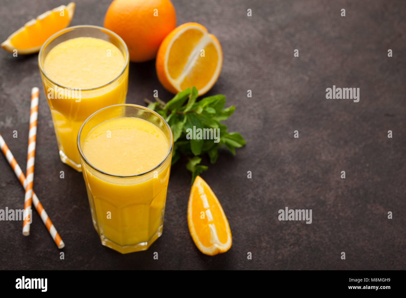 Zwei Gläser frisch gepressten Orangensaft und Minze auf einem dunklen braunen Hintergrund. Ansicht von oben mit der Kopie Raum Stockfoto