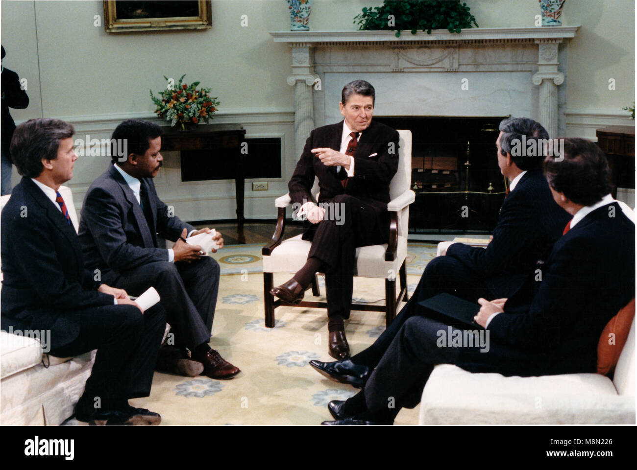 Präsidenten der Vereinigten Staaten Ronald Reagan macht einen Punkt in einem Interview mit dem Fernsehsender Anker im Oval Office des Weißen Hauses in Washington, D.C., am Donnerstag, 3. Dezember 1987. Sitzend, von links: Tom Brokaw, NBC; Bernard Shaw von CNN; Präsident Reagan; Dan eher von CBS, und Peter Jennings von ABC. .Mandatory Credit: Bill Fitz-Patrick - White House über CNP/MediaPunch Stockfoto