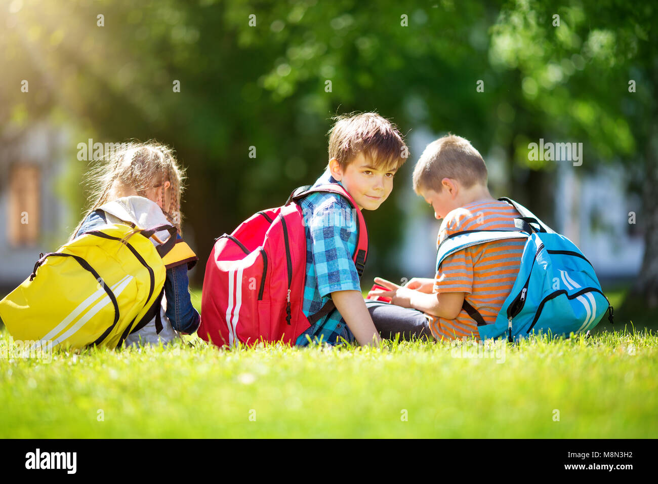 Kinder mit Rucksäcken stehen im Park in der Nähe von Schule Stockfoto