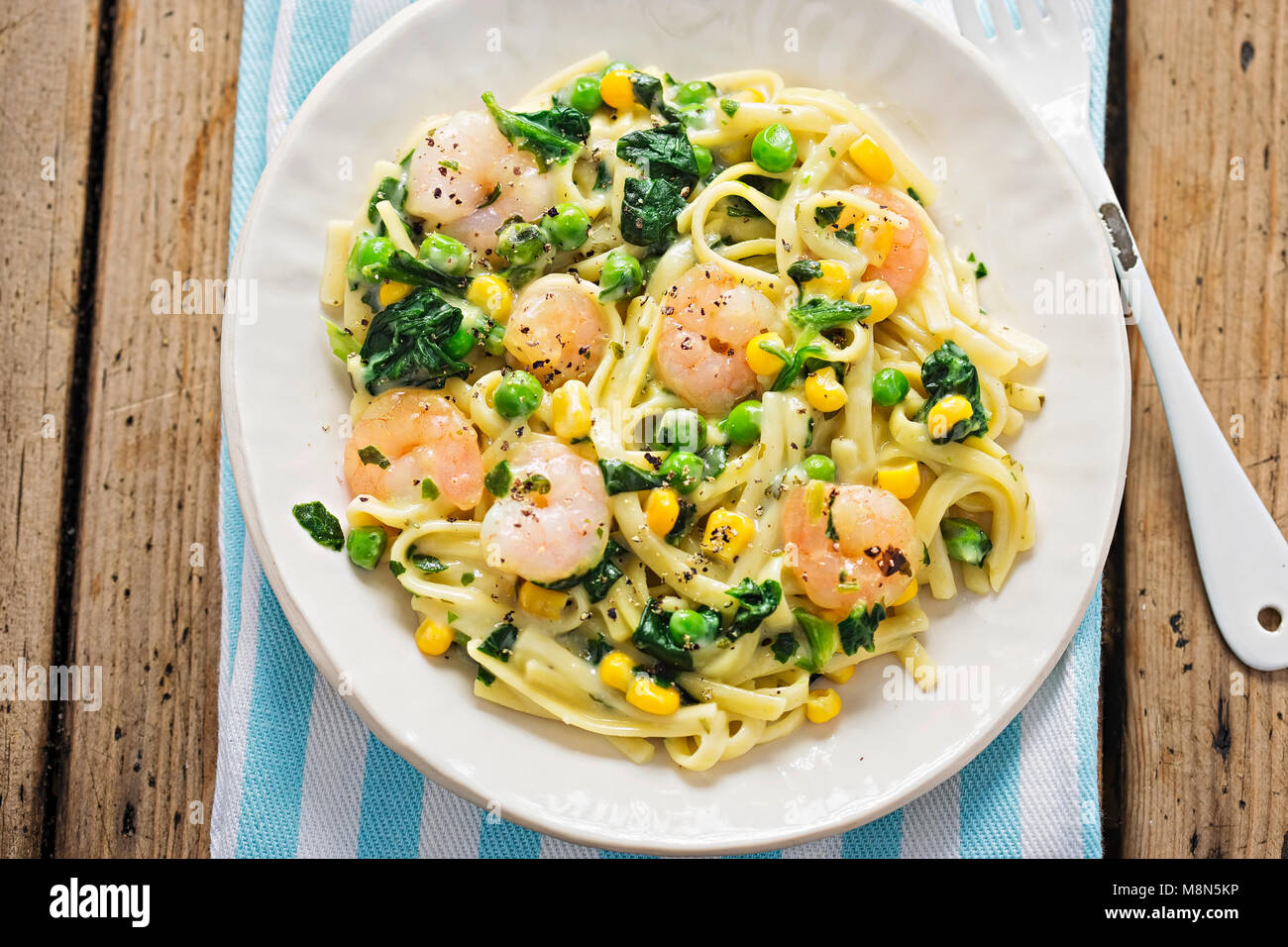 Cremige King Prawn Tagliatelle mit Erbsen, Spinat und Mais Stockfoto