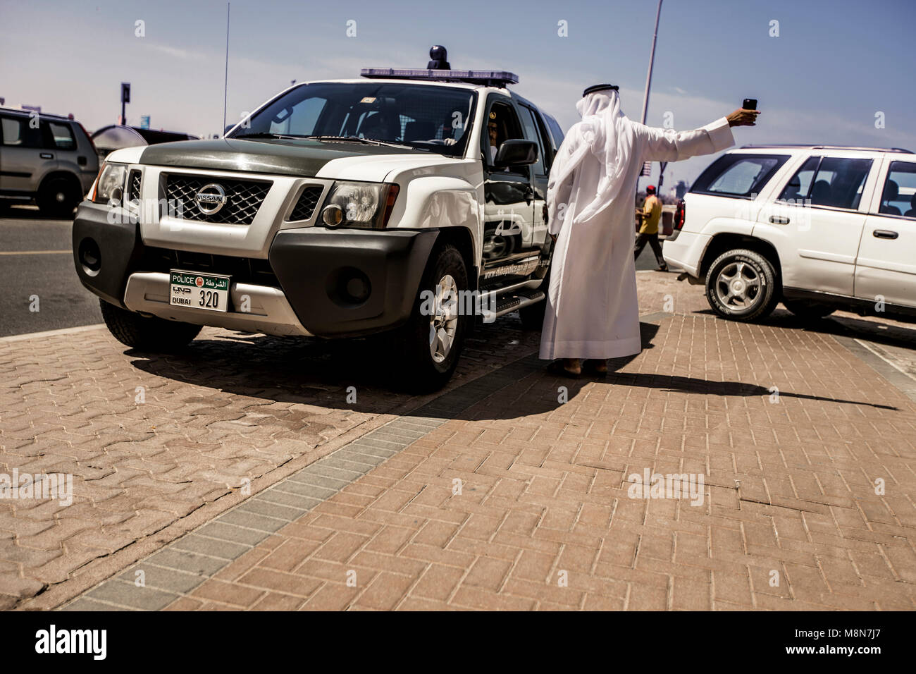 Mann waring thawb Gespräch mit der Polizei in das Polizeiauto, Dubai, VAE Stockfoto