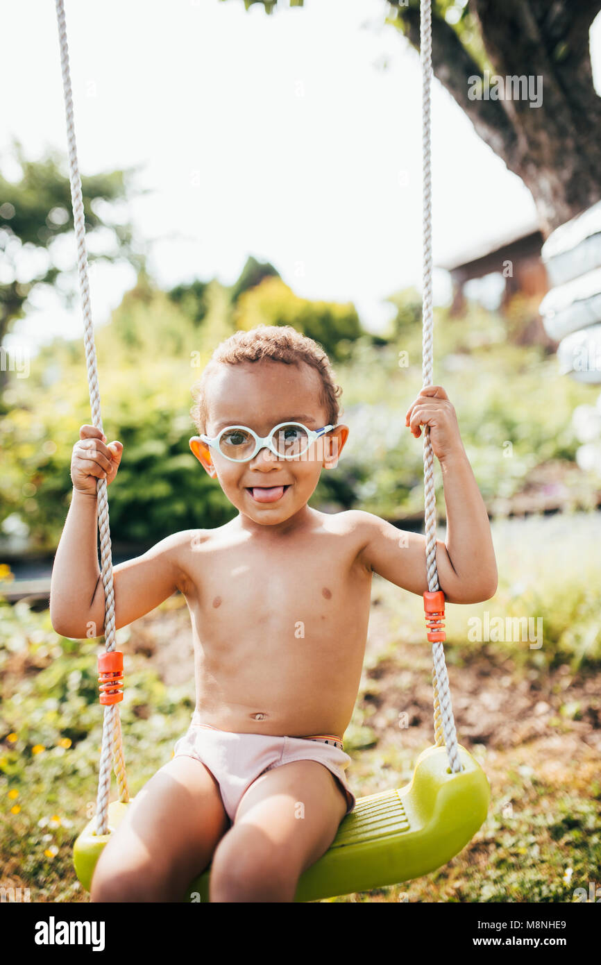 Cute black boy Spaß auf einer Schaukel im Garten seiner Eltern Stockfoto