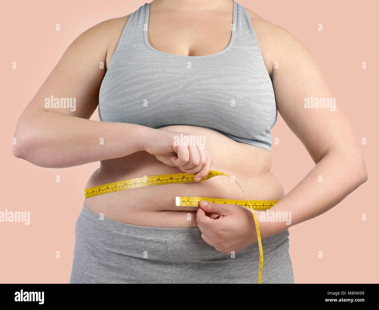 Übergewichtige Frau, die ihre Taille Messen mit dem Maßband. Stockfoto