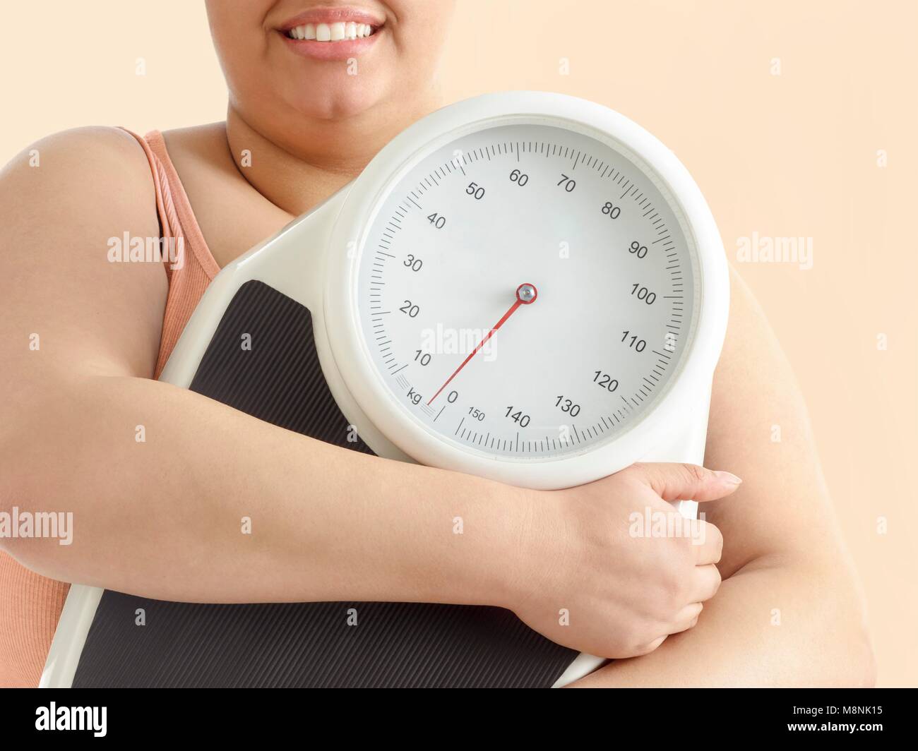 Übergewichtige Frau mit Waage, lächelnd. Stockfoto