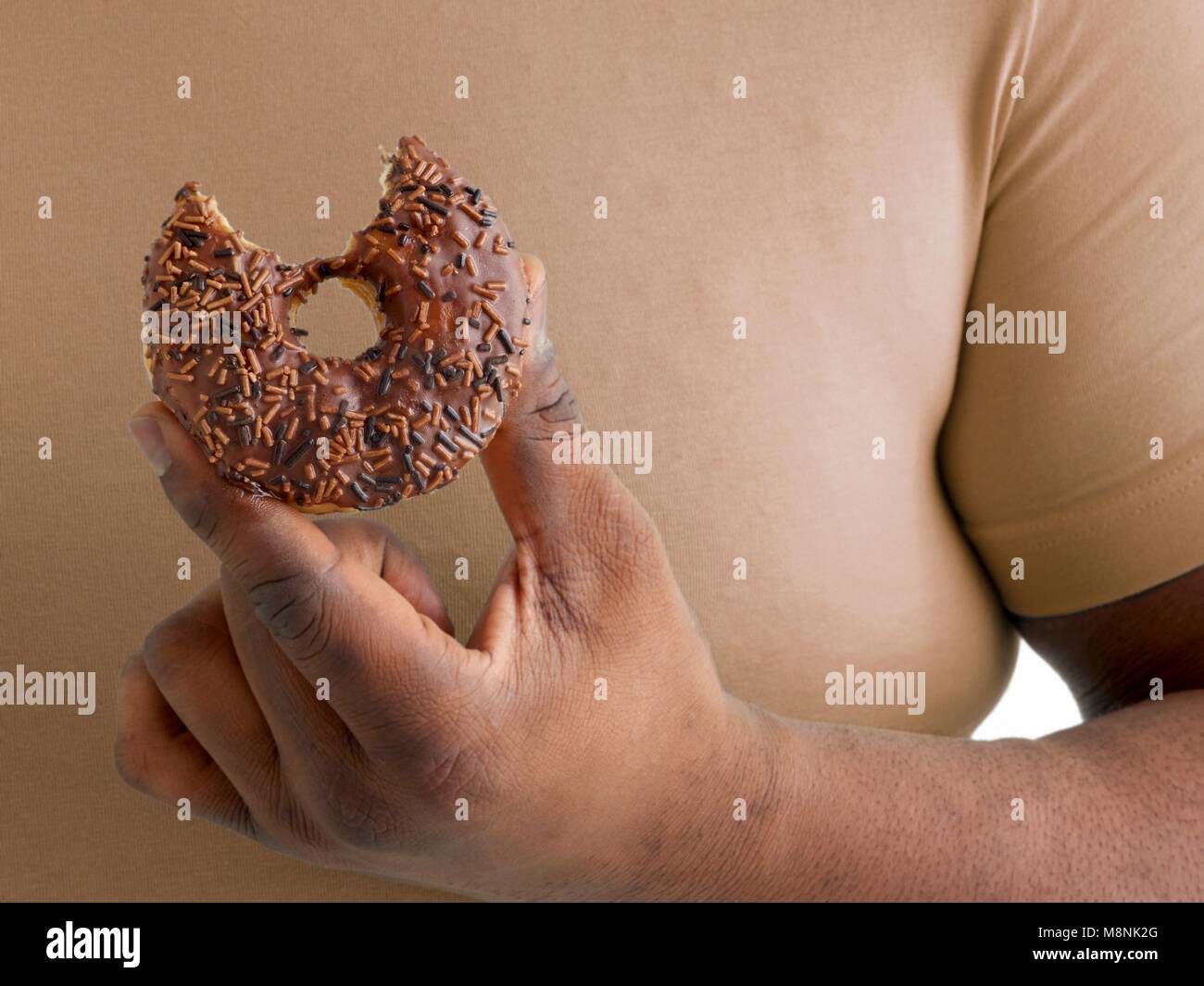 Übergewicht Mann hält einen Donut mit einem fehlenden Biss. Stockfoto
