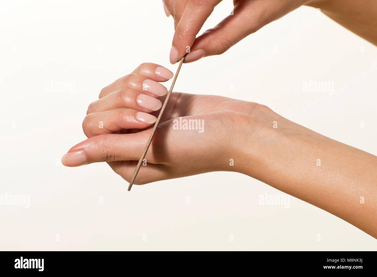 MODEL RELEASED. Junge Frau feilen Fingernägel mit Nagelfeile. Stockfoto