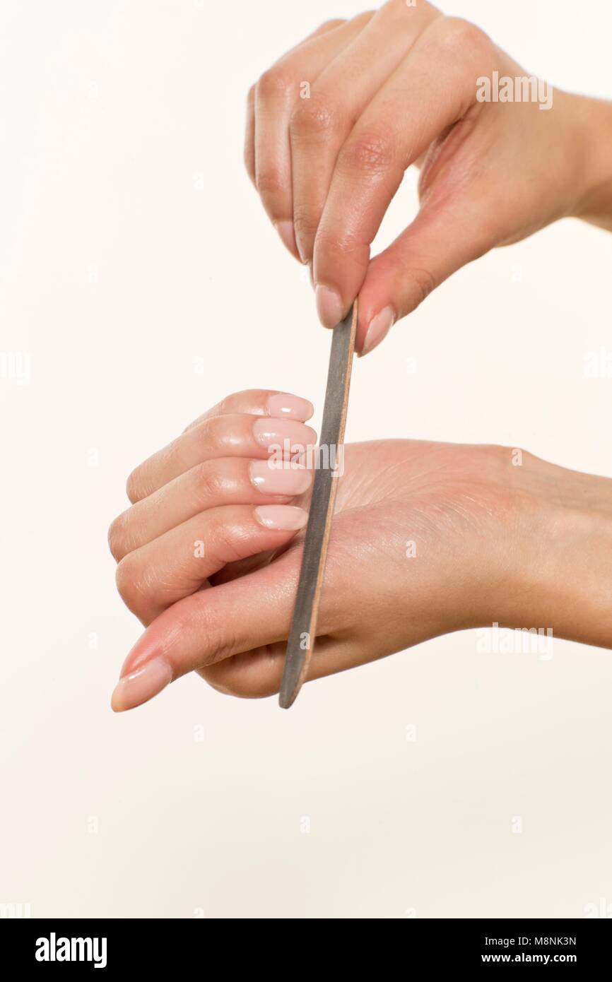 MODEL RELEASED. Junge Frau feilen Fingernägel mit Nagelfeile. Stockfoto