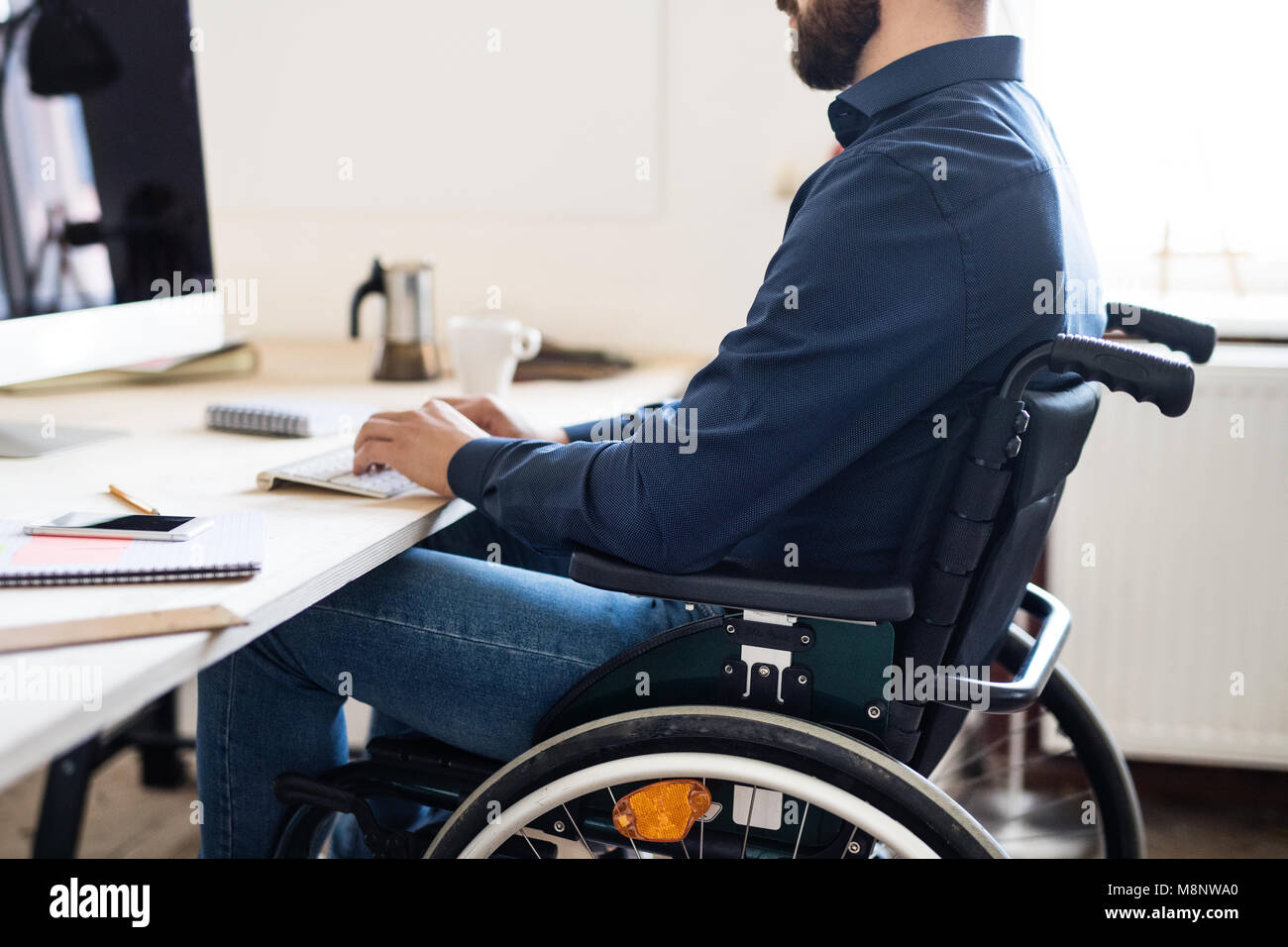 Unternehmer im Rollstuhl arbeiten in seinem Büro. Stockfoto
