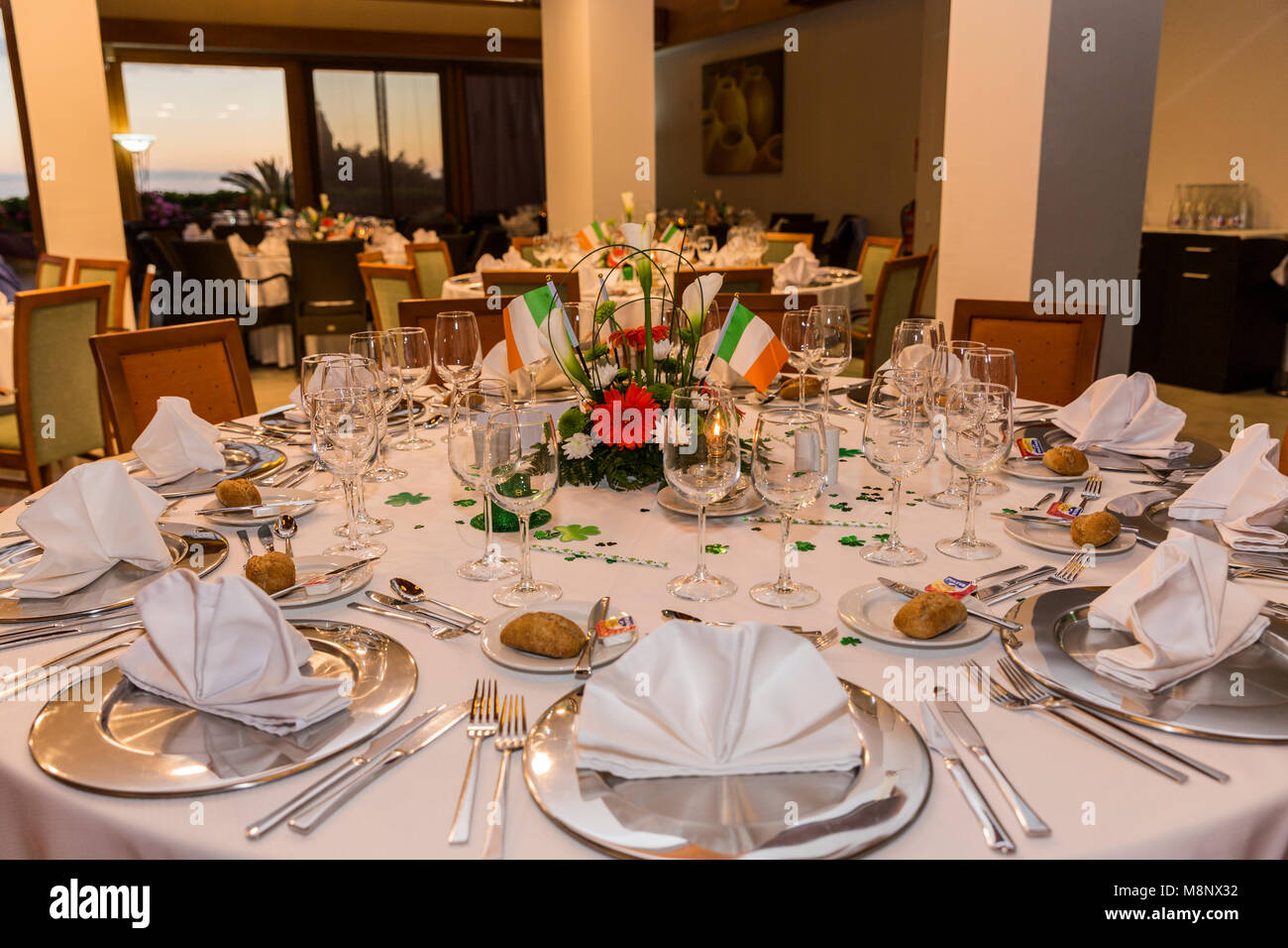 Runder Esstisch mit Besteck und Gläser, Zentrum Stück grün, weiß, orange Blüten, die Irische trikolore Fahnen und Shamrocks, für eine Saint P Stockfoto