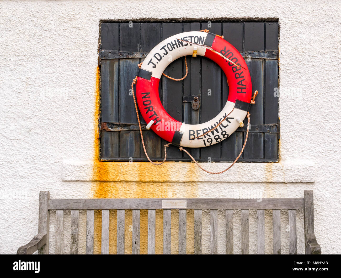 Alten roten und weißen 1988 zerrissen Leben Riemen auf Fensterläden mit Holzbank, North Berwick Hafen, East Lothian, Schottland, Großbritannien Stockfoto