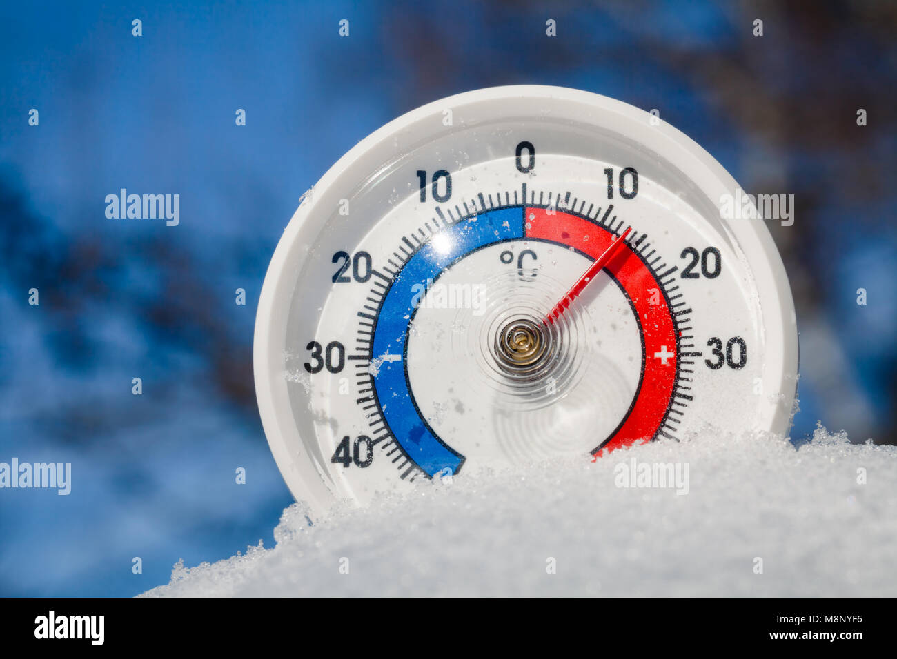 Thermometer mit Celsius im schmelzenden Schnee mit plus 13 Grad Celsius warmen Wetter im Frühling oder die globale Erwärmung Konzept Stockfoto