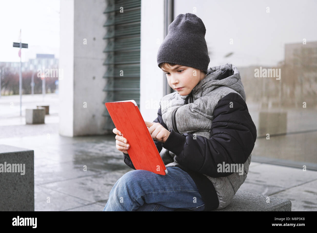 7 Jahre alten Jungen spielen online Spiel auf Tablet-PC im Winter Stockfoto